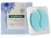 Packaging and a pair of blue Klorane eye patches designed for smoothing and soothing the skin around the eyes.